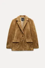 Blazer marrón de piel de ante, con cuello solapa, manga larga, bolsillos delanteros con solapa, forro interior a tono, abertura en la espalda y cierre frontal con botones.