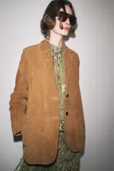 Blazer de cuero color marrón, con cuello solapa de muescas y manga larga. Bolsillos delanteros ocultos en costura y cierre frontal con botones.