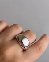 Anillo ancho tipo banda, con acabado liso y pulido, de forma convexa y redondeada.