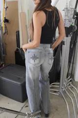 Pantalón de jean recto color gris oscuro, de tiro medio, con costuras verticales y bordado de brújula en los bolsillos traseros.