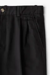 Pantalón de vestir negro con pliegues, corte recto y bolsillos laterales.