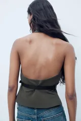 Top de cuello halter color verde oscuro, con escote pico, falso bolsillos de vivo en delantero y cinturón negro con hebilla metálica. Cierre frontal con cremallera oculta.