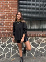 Camisa negra con cuello redondo, mangas largas abullonadas y detalle de bordado en el pecho.
