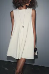 Vestido corto color crema con escote en V y sisas anchas. Tiene forro interior combinado a tono.