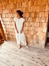 Vestido tejido color blanco con hilo metalizado, corte oversized, mangas cortas y flecos en el ruedo.