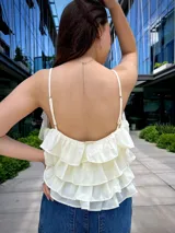 Blusa color amarillo manteca con breteles finos, escote en V con detalle de encaje y volados en capas.