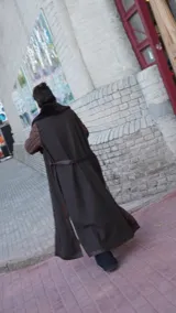 Abrigo largo marrón con mangas de cuero acolchado, cuello de piel sintética y cinturón de cuero.