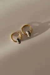 Par de aros tipo argolla dorados con dije de piedra natural con patrón de manchas negras sobre fondo blanco.