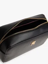 Cartera cruzada tipo cámara de poliuretano negro, con cierre principal de cremallera y monograma TH metálico dorado al frente. Incluye correa larga ajustable con cinta distintiva de rayas azul, blanco y rojo.