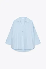 Camisa marrón de popelina con cuello solapa, escote en pico, cierre frontal con botones y mangas anchas con puños.