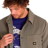 Chaqueta negra de twill de algodón con cierre frontal a presión, bolsillos superiores en el pecho y en la parte inferior, puños elásticos, forro con logo de Caterpillar y bolsillo interior en el pecho.