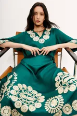 Vestido tipo túnica largo midi de viscosa color verde esmeralda con bordados florales en color crema. Tiene mangas al codo y lazo de ajuste en la cintura.