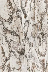 Camisa semitransparente con estampado animal print en tonos beige y marrón, de cuello redondo y escote pico, con mangas largas abullonadas. Detalle de volantes e hilo metalizado. Cierre frontal con botones.