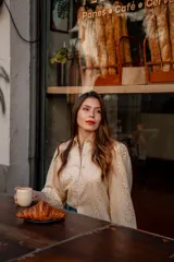 Camisa color beige con bordado inglés, de corte recto, manga larga abullonada con puño y cuello camisero.