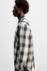 Camisa de hombre regular fit confeccionada en tejido de algodón a cuadros en tonos azul oscuro y verde oliva. Tiene cuello solapa, manga larga con puños abotonados, bolsillo de plastrón en el pecho y cierre frontal con botones.