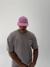 Gorro tipo béisbol color rosado con visera, bordado frontal con la palabra "AUTHENTIC" en azul y un perro dálmata en blanco y negro.