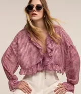 Blusa de chiffon con estampado pied de poule en tonos rosado y borgoña. Presenta escote en V con volados, mangas largas con puños elásticos y corte cropped con volados en el ruedo.
