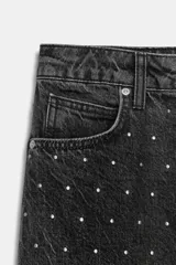 Jeans de tiro alto, corte recto y largo, color negro lavado, con abalorios brillantes distribuidos por toda la prenda.