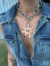 Collar con cadena plateada de eslabones grandes y dije abstracto de acrílico y resina color beige y marrón. El dije es desmontable.