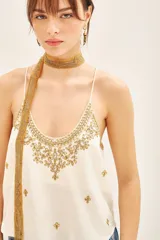 Top blanco con bordados dorados, cuello redondo y breteles finos.