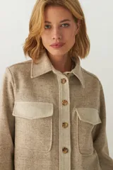 Camisa estilo leñador color beige con textura de espiga, de manga larga con puños abotonados, cuello clásico, cierre frontal con botones y dos bolsillos de parche con solapa abotonada en el pecho.