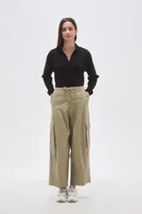 Pantalón cargo de algodón color verde oliva, tiro bajo, con cintura ajustable mediante cordón y piernas anchas y rectas. Presenta bolsillos cargo en los laterales.