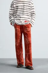 Pantalón relaxed fit de punto ligero tejido en hilatura de algodón color ladrillo con estampado a cuadros difuminados en blanco. Cintura elástica ajustable con cordón y bolsillos laterales.