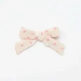 Pack de dos pinzas para el pelo con forma de moño, una celeste lisa y otra color crema con estampado de flores rosas.