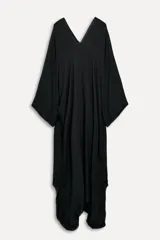 Vestido tipo capa color negro confeccionado en hilatura de viscosa, con escote pico, manga corta y bajo asimétrico desflecado.