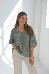 Blusa verde con estampado de flores blancas, cuello en V y mangas cortas.
