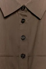 Vestido midi color marrón, sin mangas, con cuello solapa, cierre frontal de botones y falda con pliegues. Presenta un bolsillo con solapa en el delantero.