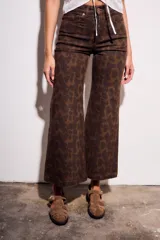 Pantalón de jean tiro medio, corte wide leg acampanado, color marrón oscuro con estampado animal print en tonos más oscuros y pequeños puntos rosados.