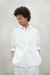 Camisa blanca de lino con corte clásico, cuello camisero y mangas largas con puños abotonados.