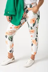Pantalón babucha blanco con estampado de flores y hojas en tonos naranja, marrón y verde.