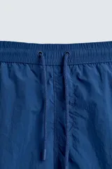 Short de baño azul con cintura elástica ajustable con cordón, bolsillos laterales y bolsillo trasero de plastrón.