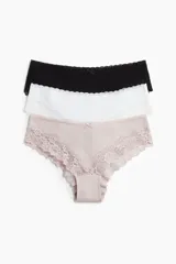 Pack de tres bombachas hipster de algodón con cintura estándar y cobertura media. Incluye una bombacha negra, una blanca y una rosa pálido, todas con detalles de encaje en los bordes.