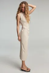 Vestido midi color blanco hueso, sin mangas, con cuello alto y detalle de drapeado fruncido en el lateral izquierdo del torso.