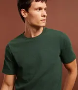 Remera verde oscuro de corte slim, cuello redondo y manga corta. Confeccionada en algodón texturizado.