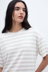 Remera holgada a rayas horizontales color crudo y beige, con mangas cortas y tajos laterales.
