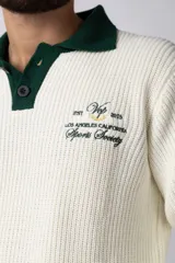 Sweater de punto verde con cuello polo color crema y bordado frontal con texto en blanco.