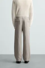 Pantalón de vestir color blanco hueso, de corte recto y tiro medio, con cintura elástica y cierre frontal de botón y cremallera. Presenta bolsillos frontales y bolsillos traseros de vivo.