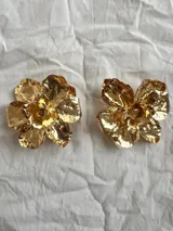 Par de aros dorados con forma de flor con textura martillada.