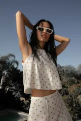 Conjunto de lino blanco con lunares dorados, compuesto por top sin mangas con volado y falda corta con cierre lateral.