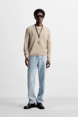 Jersey de punto color beige, con cuello en V y mangas largas.