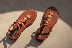 Sandalias de cuero color naranja con tiras finas y apliques de flores en la tira central.