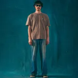 Remera oversize color beige con efecto gastado, cuello redondo y estampado pequeño en el pecho con el logo de la marca Kaboa Industries y la frase 'Más barrio que moda'.