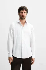 Camisa de vestir slim fit de algodón, color blanco con diseño de cuadros en tonos grises y beige. Tiene cuello italiano, mangas largas con puños abotonados y cierre frontal con botones.