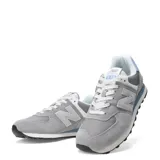 Championes urbanos New Balance modelo 574, color gris con detalles en celeste y blanco, confeccionados en gamuza y malla, con logo "N" característico en los laterales y entresuela ENCAP.