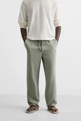 Pantalón color arena de corte recto, confeccionado en tejido de algodón y lino. Cuenta con cintura elástica ajustable con cordón, bolsillos delanteros y traseros de parche.