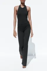 Mono largo negro de tejido elástico, con cuello halter, espalda descubierta y bajo acampanado.